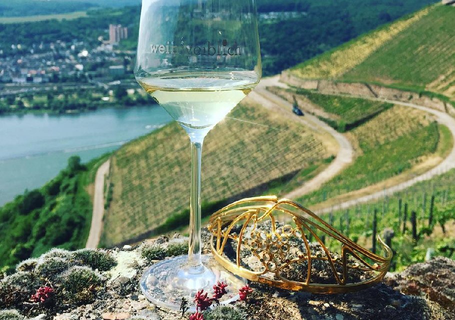 前景是一杯德国白葡萄酒，远处是陡峭的葡萄园