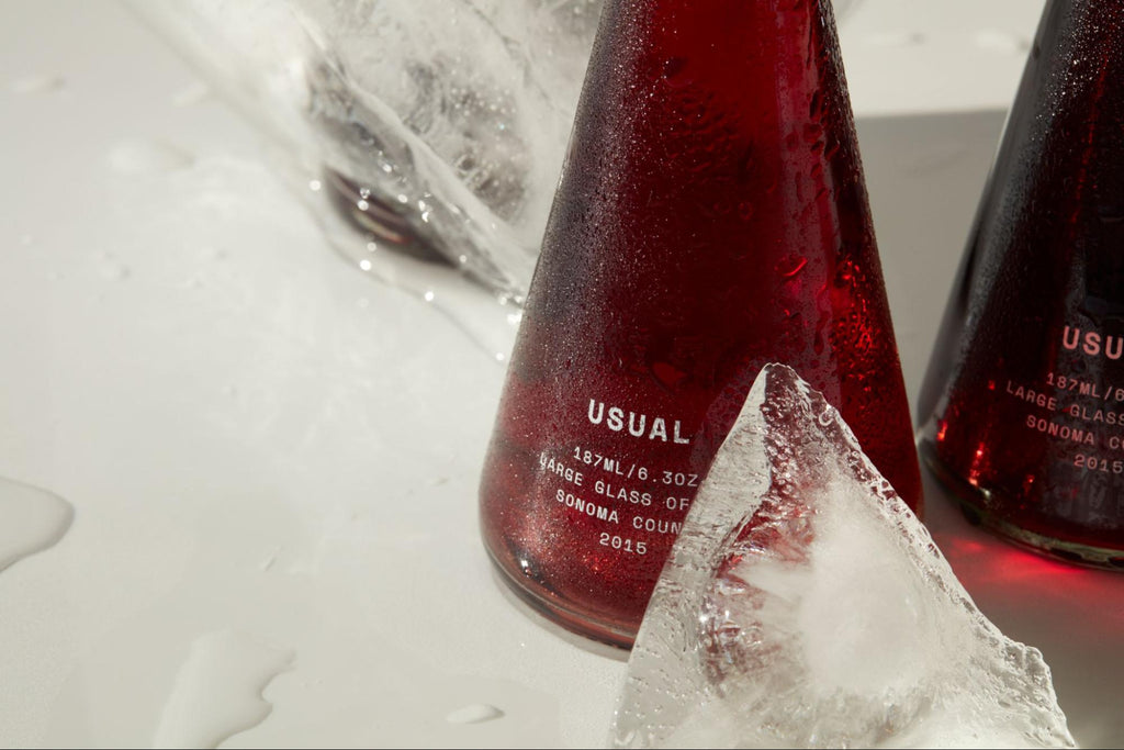 两瓶来自 Usual Wines 的红酒，旁边有碎冰